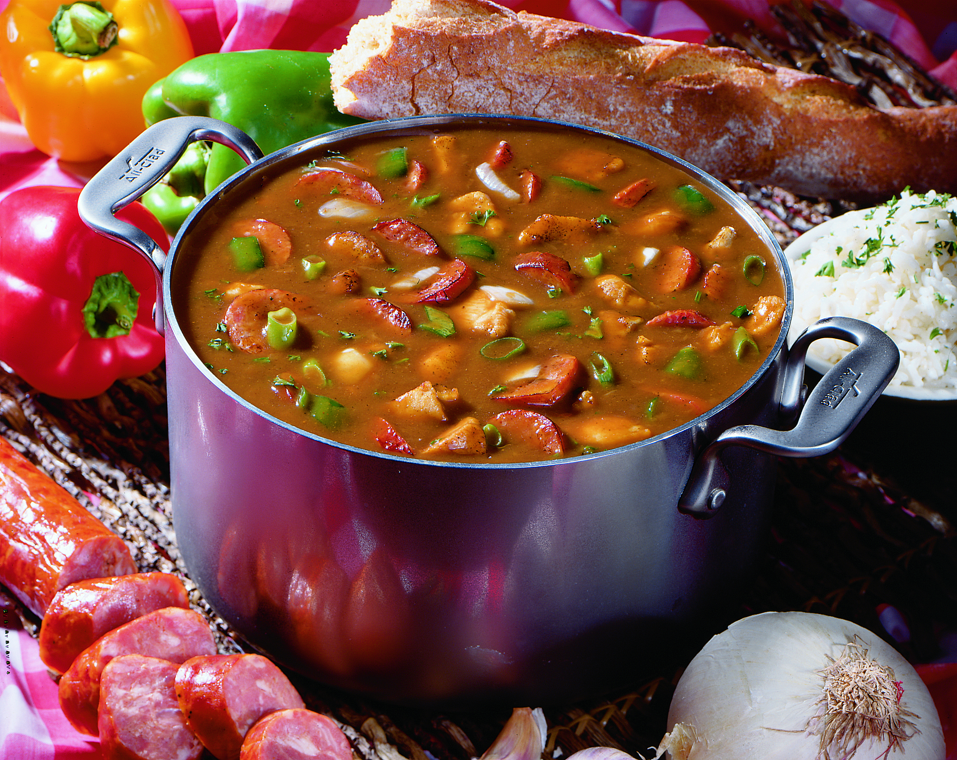 Pot of Tony's Easy Gumbo, surrounded by ingredients and crusty baguette bread