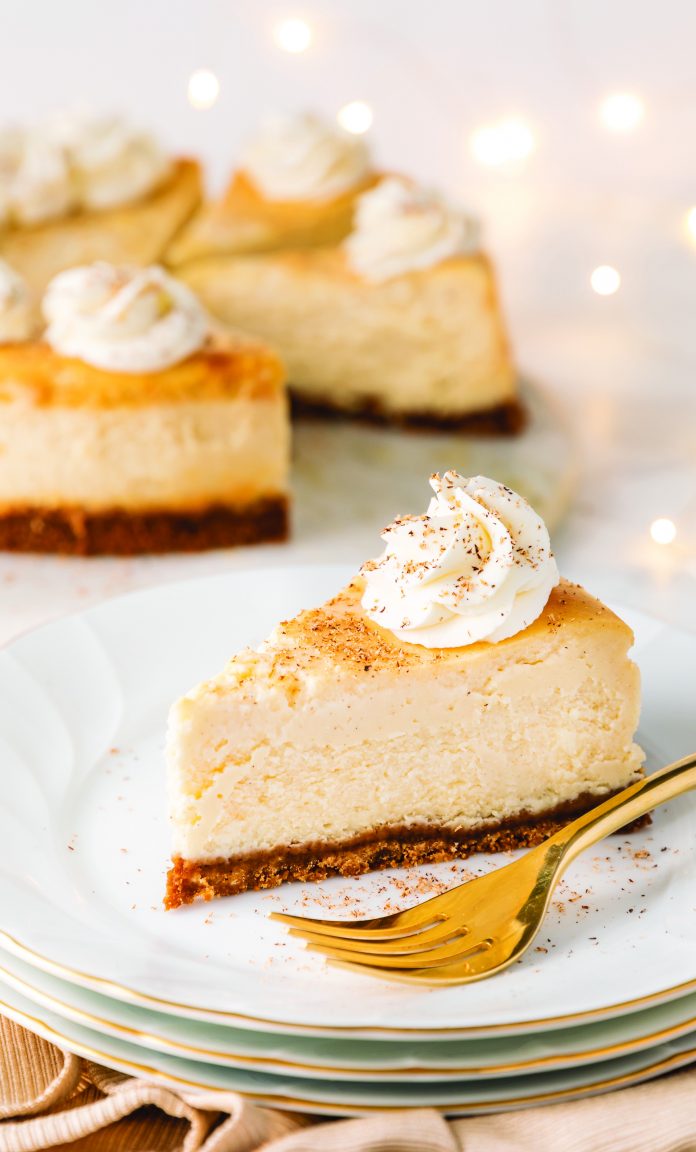 A slice of decadent eggnog cheesecake with a dollop of whipped cream and dusting of nutmeg and cinnamon