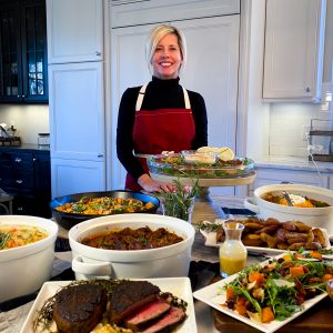Monica Bissmeyer, CEO, posing with a holiday feast, smiling.